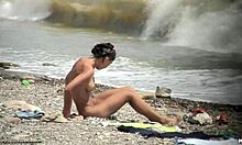 Seorang wanita telanjang berambut gelap berjalan telanjang di pantai