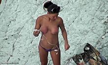 Rondborstige hardbody hottie poseert topless op een strand