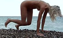 Bionda che si mette in posa completamente nuda su una spiaggia rocciosa