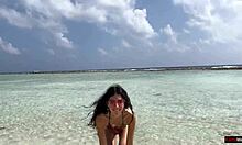 Прелепа девојка пиша под златним тушем на плажи на Малдивима